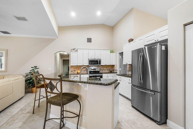 2020 Newhaven Ave, Wellington, FL 33414 - kitchen with stainless steel appliances, light tile patterned floors, a kitchen breakfast bar, white cabinets, and tasteful backsplash
