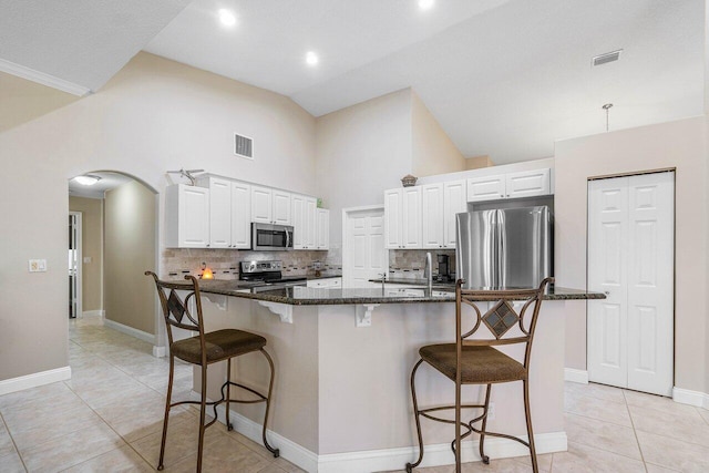 2020 Newhaven Ave, Wellington, FL 33414 - kitchen featuring appliances with stainless steel finishes, arched walkways, dark stone countertops, white cabinets, and high vaulted ceiling