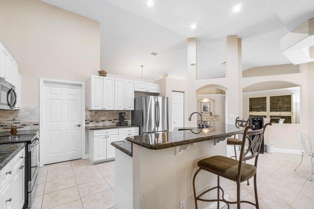 2020 Newhaven Ave, Wellington, FL 33414 - kitchen with stainless steel appliances, a breakfast bar, backsplash, light tile patterned floors, and high vaulted ceiling