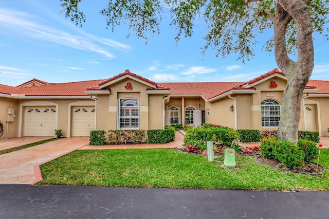 mediterranean / spanish-style house featuring a front yard, a tiled roof, a garage, concrete driveway, and stucco siding