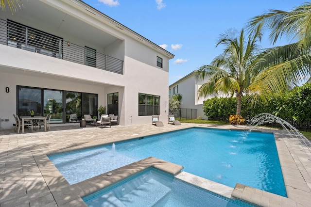 view of swimming pool with a pool with connected hot tub, fence, and a patio