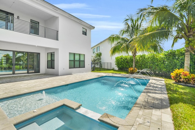 view of swimming pool with a patio, a pool with connected hot tub, and fence