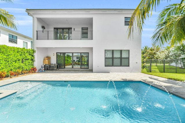rear view of property featuring stucco siding, fence, a patio area, and a balcony