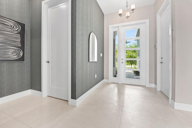 entrance foyer with a chandelier, baseboards, and light tile patterned floors