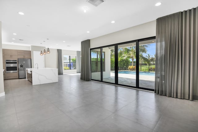 unfurnished living room with a wealth of natural light, recessed lighting, an inviting chandelier, and visible vents