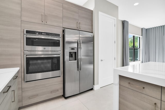 kitchen featuring light stone countertops, appliances with stainless steel finishes, modern cabinets, and light tile patterned floors