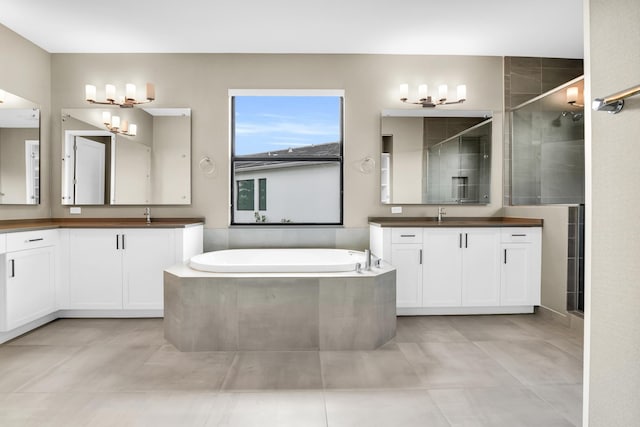 full bath featuring a garden tub, a chandelier, a stall shower, and a sink