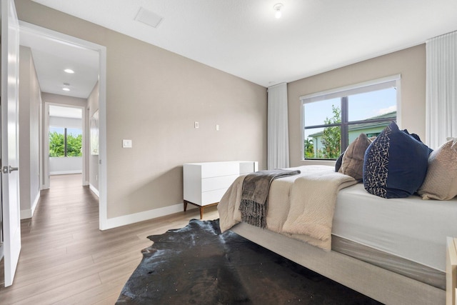 bedroom featuring baseboards, multiple windows, light wood-type flooring, and visible vents