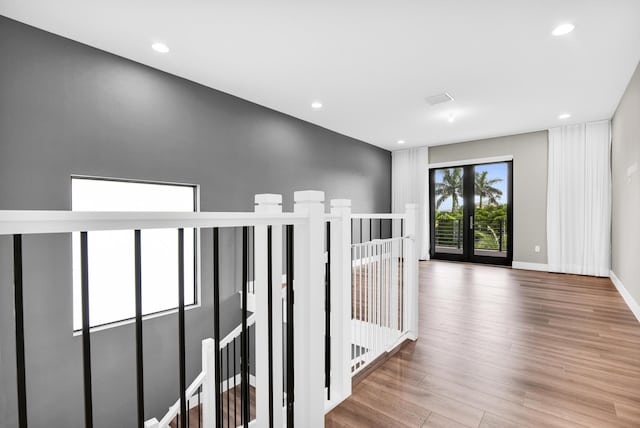 hall with baseboards, an upstairs landing, recessed lighting, and wood finished floors