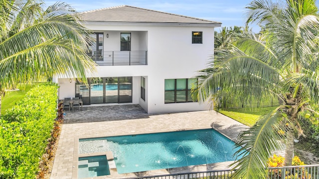 rear view of property featuring fence, a balcony, a patio, stucco siding, and a fenced in pool