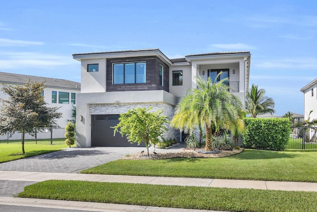 view of front of home featuring stucco siding, an attached garage, fence, and decorative driveway