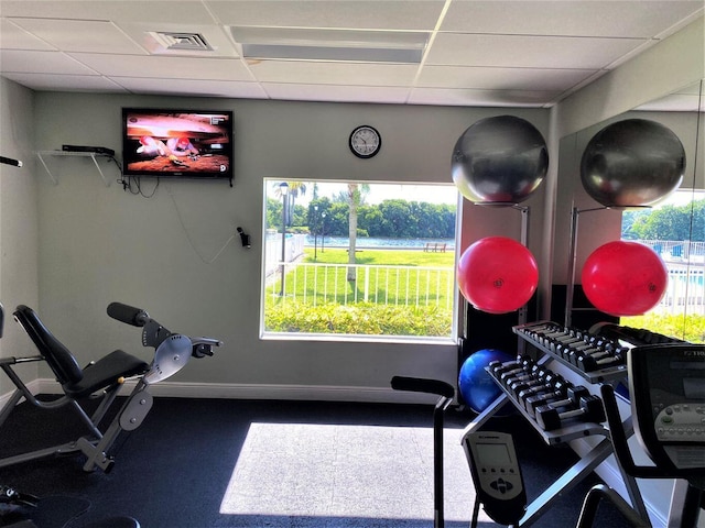 gym featuring visible vents, a drop ceiling, and baseboards