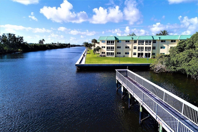 view of dock with a lawn and a water view