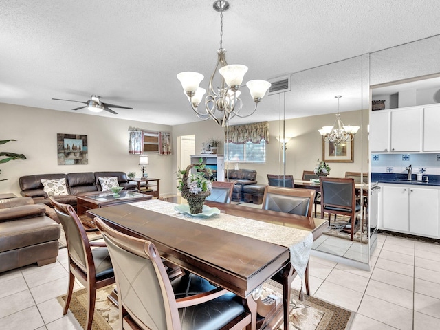 dining space with visible vents, ceiling fan with notable chandelier, light tile patterned floors, and a textured ceiling