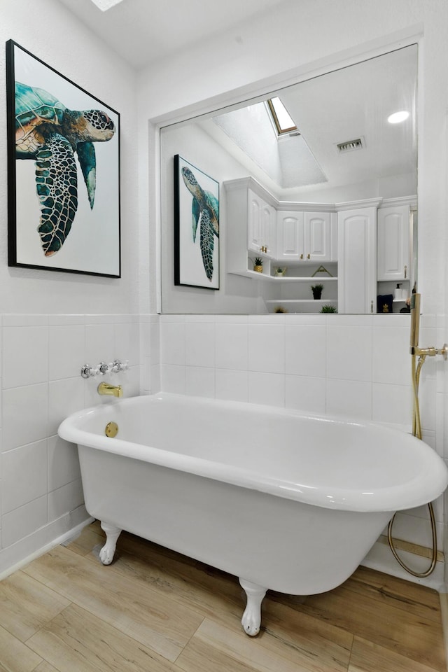 1021 N Palmway, Lake Worth Beach, FL 33460 - full bathroom with a freestanding bath, wood finished floors, tile walls, and a skylight