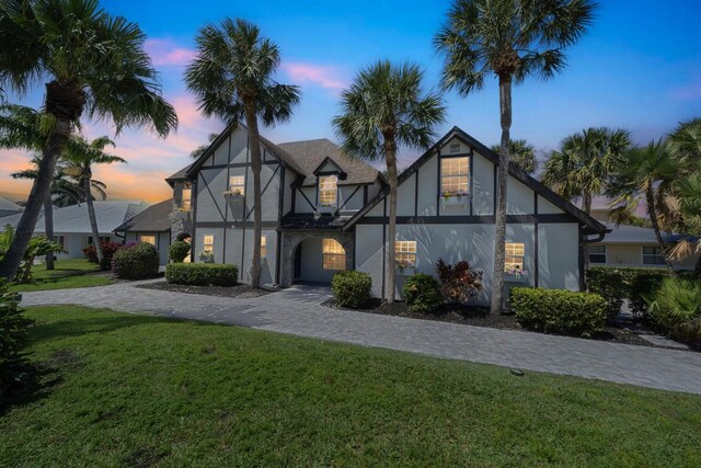 121 Queen Eugenia Ct, Hutchinson Island, FL 34949 - tudor-style house with stucco siding and a front lawn