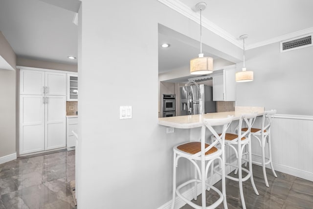 121 Queen Eugenia Ct, Hutchinson Island, FL 34949 - kitchen with visible vents, baseboards, a kitchen bar, crown molding, and stainless steel appliances