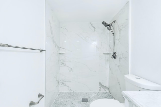 bathroom with a marble finish shower and toilet