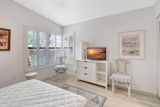 bedroom with baseboards, light wood-type flooring, and vaulted ceiling