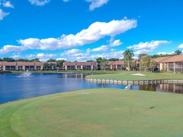 view of home's community with a lawn, view of golf course, and a water view