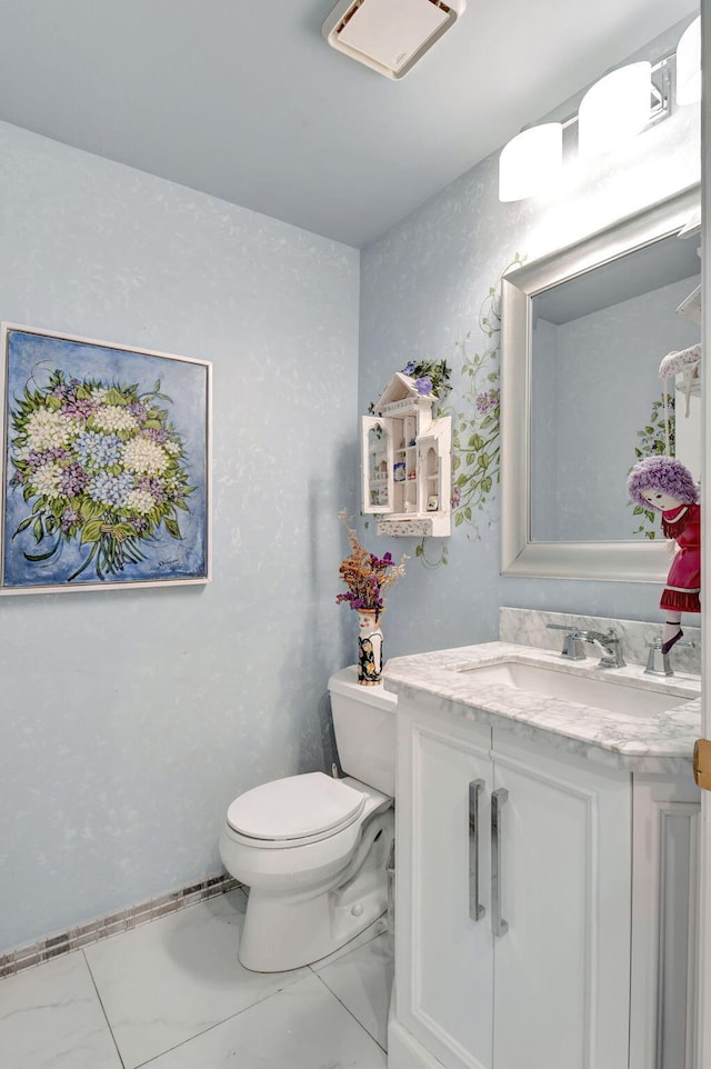 half bathroom featuring toilet, vanity, and marble finish floor