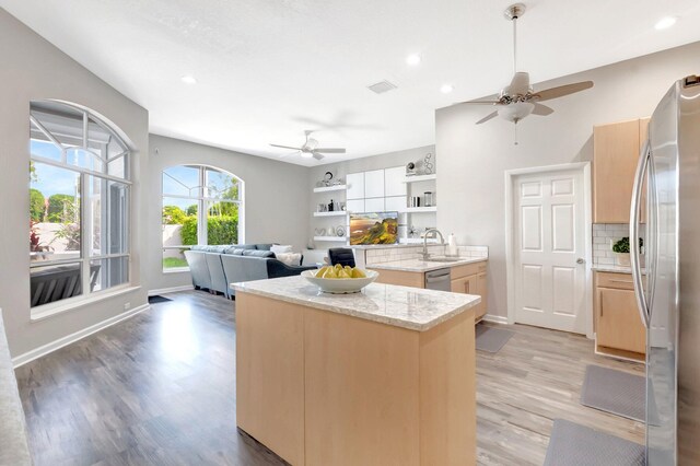 kitchen with tasteful backsplash, light wood-style flooring, appliances with stainless steel finishes, and a ceiling fan