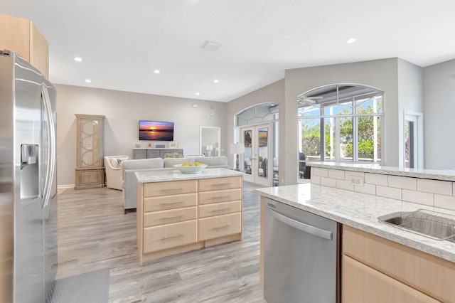 kitchen featuring open floor plan, light wood-style floors, appliances with stainless steel finishes, and light brown cabinetry