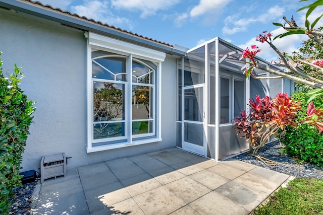 view of exterior entry featuring a patio area and stucco siding