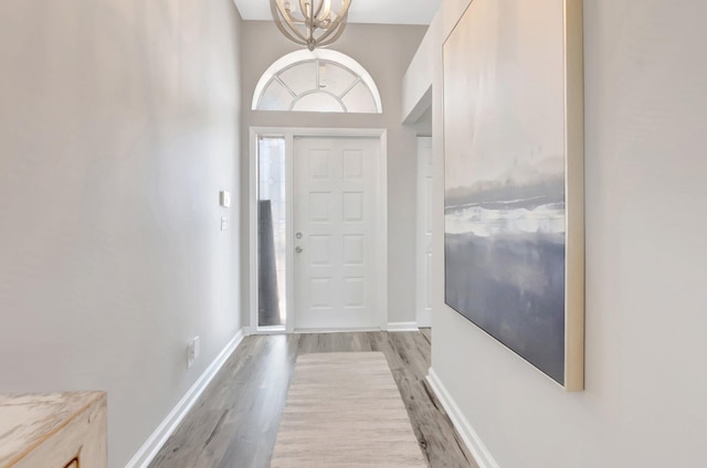 entryway with a chandelier, light wood-style floors, and baseboards