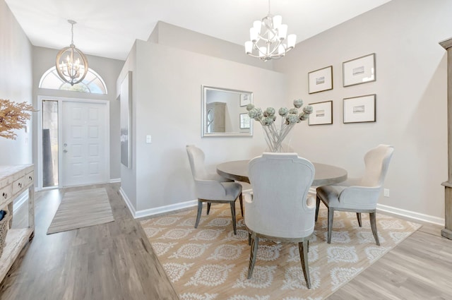 dining space with light wood-type flooring, a notable chandelier, and baseboards