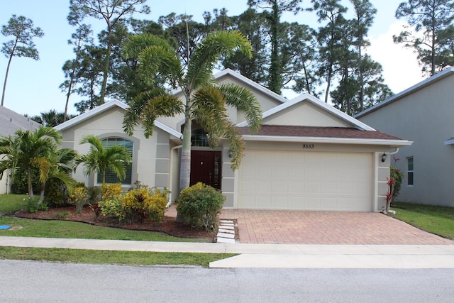 view of front facade featuring a garage, stucco siding, and decorative driveway