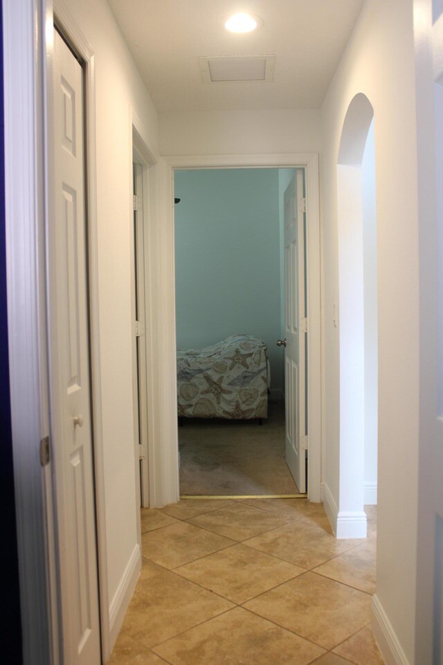 hall with recessed lighting, light carpet, attic access, light tile patterned flooring, and baseboards