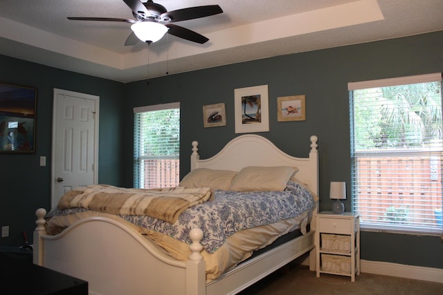 bedroom with a tray ceiling, baseboards, ceiling fan, and carpet