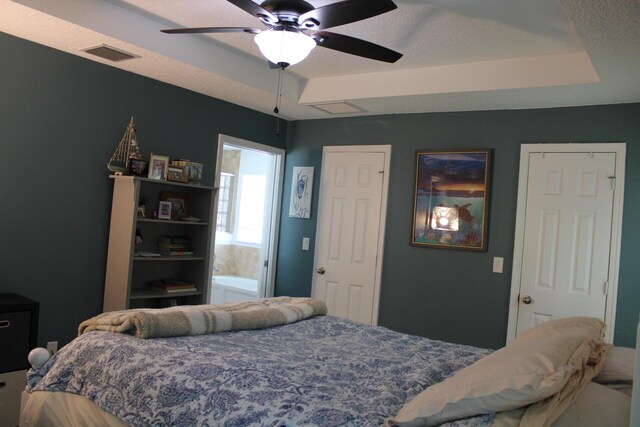 bedroom featuring visible vents, a ceiling fan, and a tray ceiling