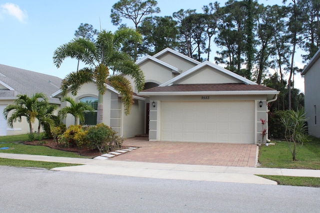 ranch-style home featuring a garage, stucco siding, decorative driveway, and a shingled roof