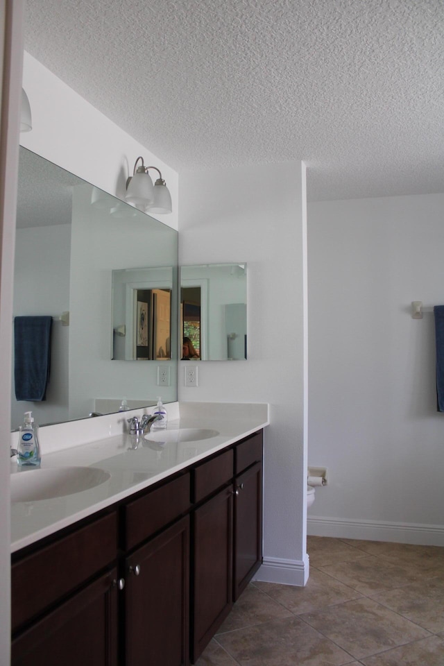 full bathroom featuring tile patterned floors, double vanity, a textured ceiling, and a sink