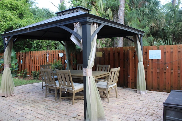 view of patio / terrace featuring a gazebo, outdoor dining area, and fence