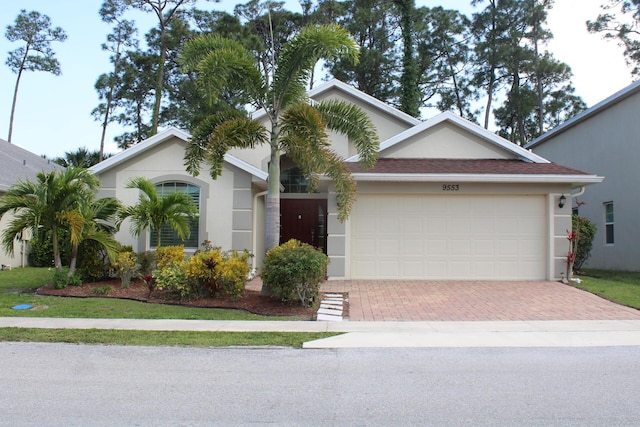 ranch-style home featuring a garage, decorative driveway, and stucco siding