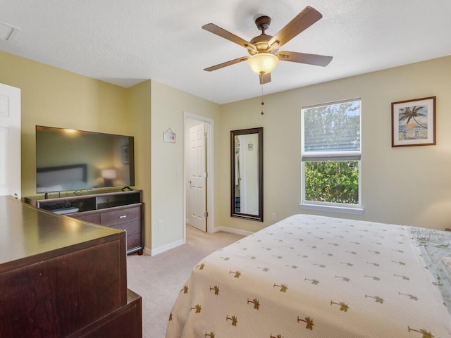 bedroom with light colored carpet, baseboards, and a ceiling fan