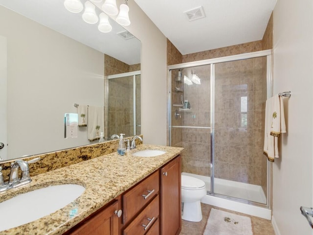 bathroom with a shower stall, toilet, double vanity, and tile patterned flooring