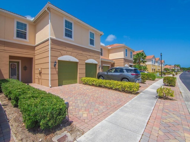 view of front of home featuring an attached garage, decorative driveway, stucco siding, and a residential view