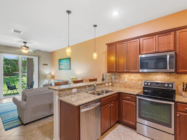 kitchen with appliances with stainless steel finishes, open floor plan, a peninsula, a sink, and decorative backsplash