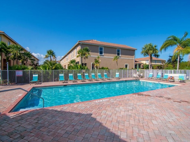community pool with fence and a patio area