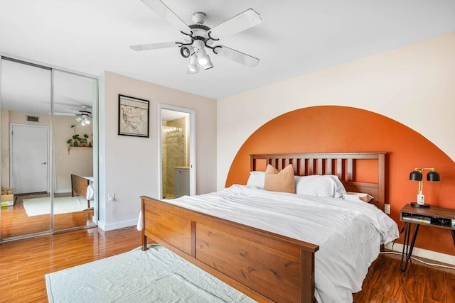 bedroom with a closet, a ceiling fan, visible vents, wood finished floors, and baseboards