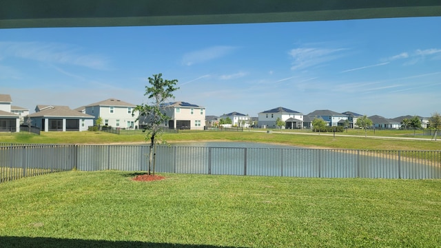view of yard with a residential view, a water view, and a fenced backyard