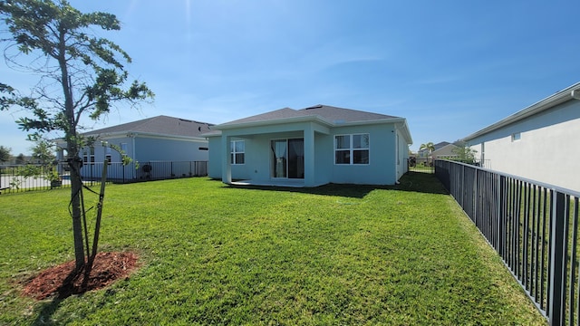 rear view of house featuring stucco siding, a yard, and a fenced backyard