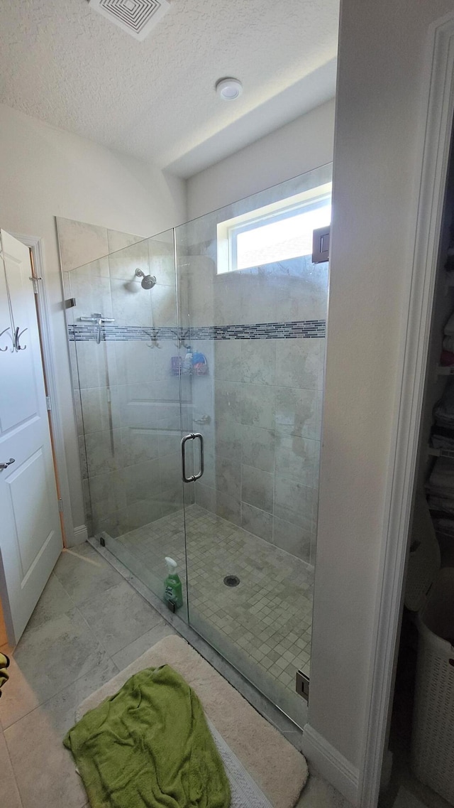 full bathroom featuring a textured ceiling, visible vents, and a shower stall