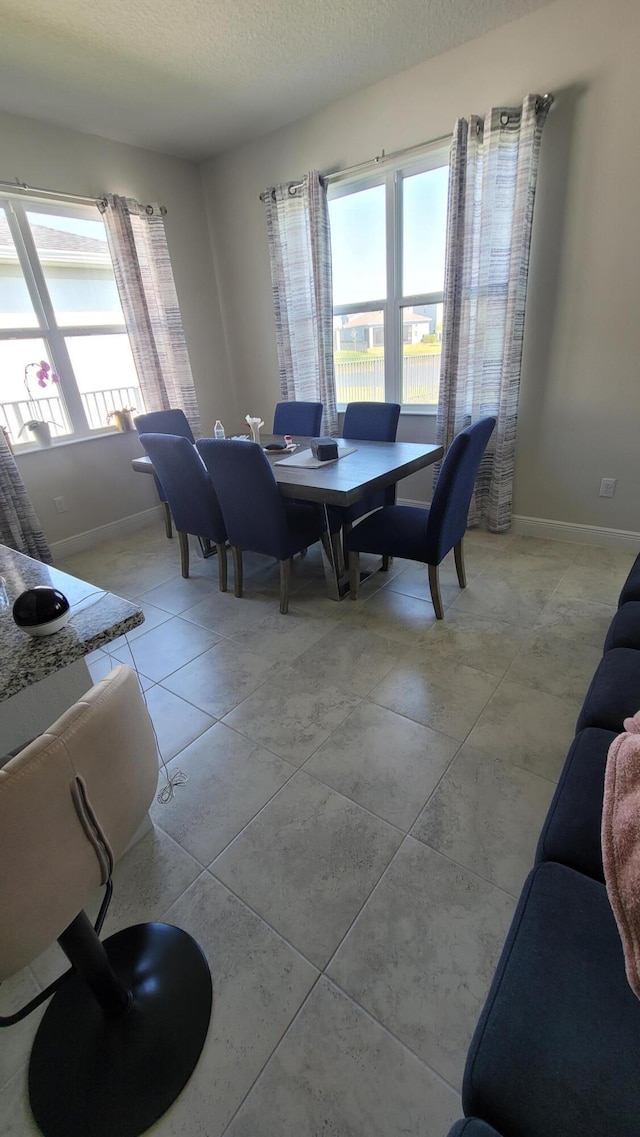 dining area featuring light tile patterned floors, a textured ceiling, and baseboards