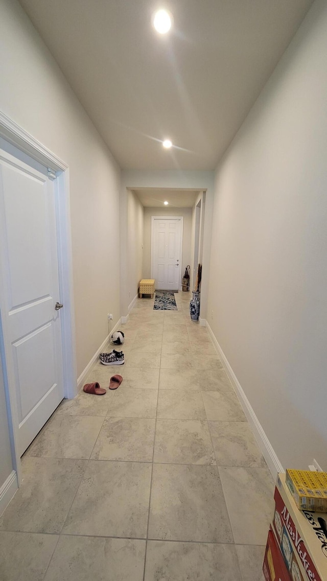 corridor featuring baseboards, recessed lighting, and light tile patterned floors