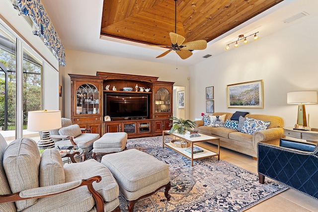 tiled living room featuring visible vents, ceiling fan, and a tray ceiling